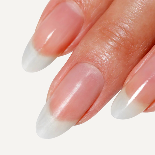Close-up of a hand with nails featuring a white tip design on a light background